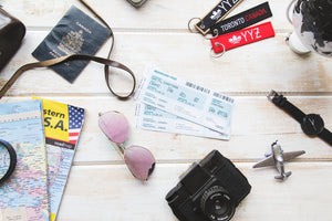 Welcome Image containing lifestyle items like a watch, flight boarding passes, travel maps, sunglasses, passports Canadian keychains, camera.